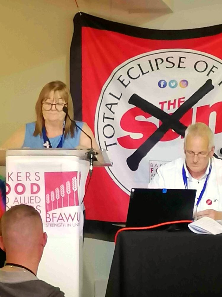 A safety rep speaking at a Hazards meeting in front of a union banner