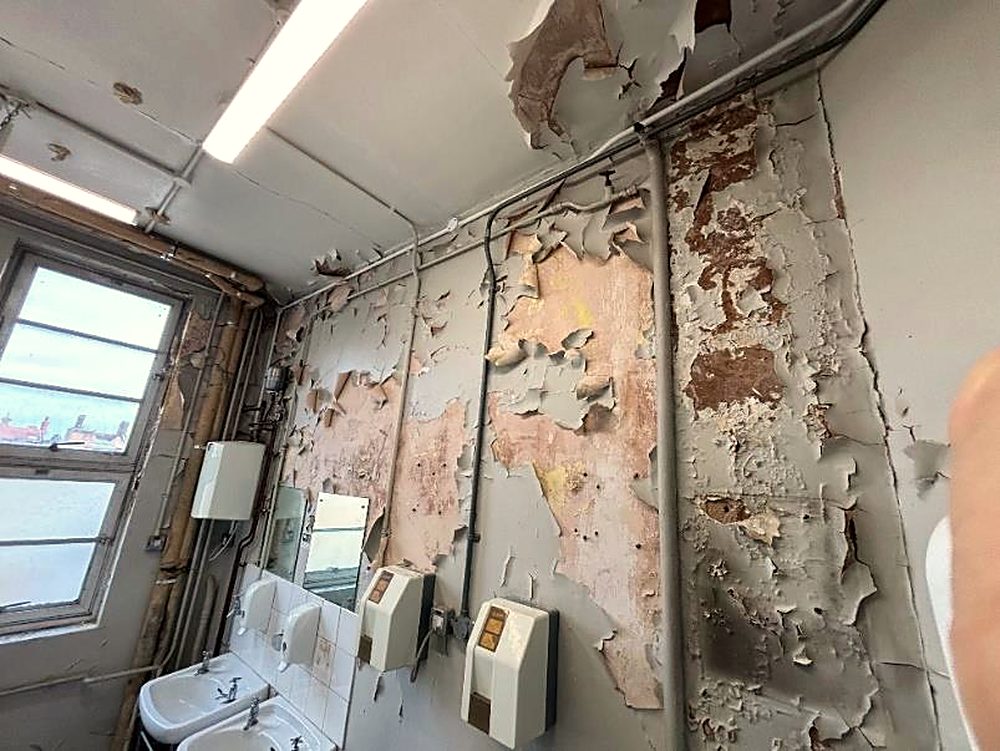 A run-down staff toilet with peeling walls
